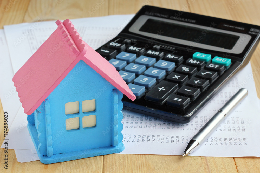 Electronic calculator with push buttons, wooden model house, metal pen and sheets of paper Electronic calculator with push buttons, wooden model house, metal pen and sheets of paper