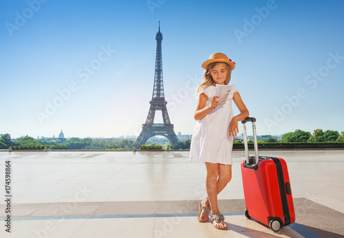 Canvas Print Little traveler with suitcase reading map in Paris