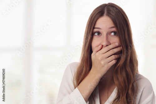 Obraz na plátne Playful, surprised, shy young woman hiding her face laughing timid