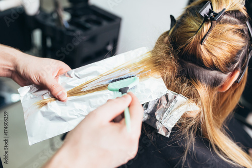 Hairdresser is dying female hair, making hair highlights to his client with a foil.  photo