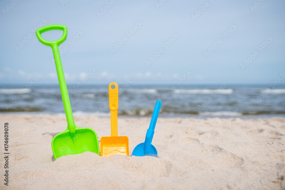 Three colorful toy shovels on the beach Three colorful toy shovels on the beach