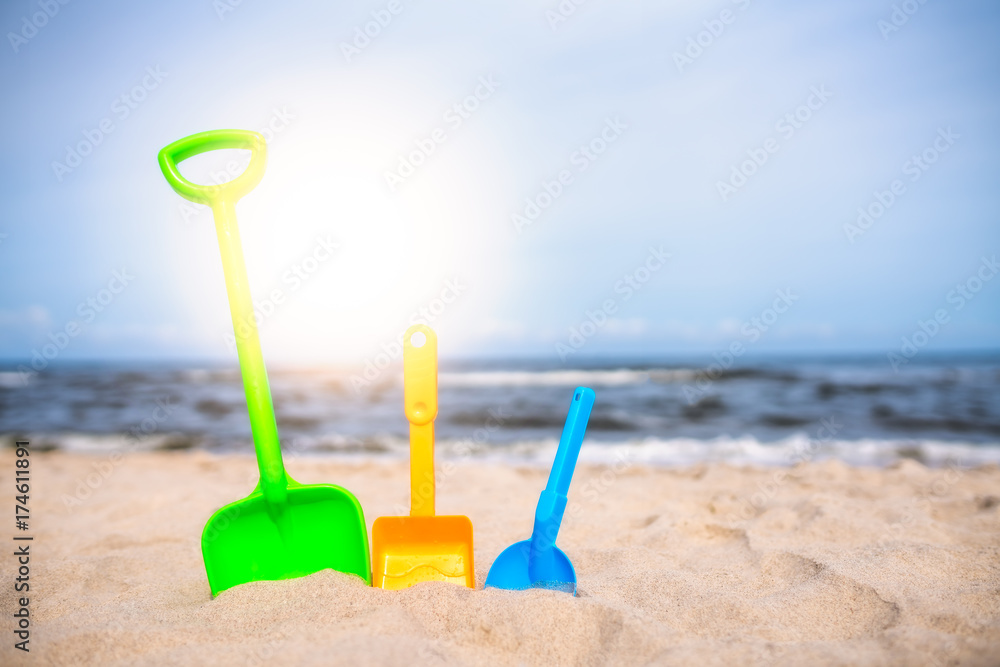 Three colorful toy shovels on the beach Three colorful toy shovels on the beach