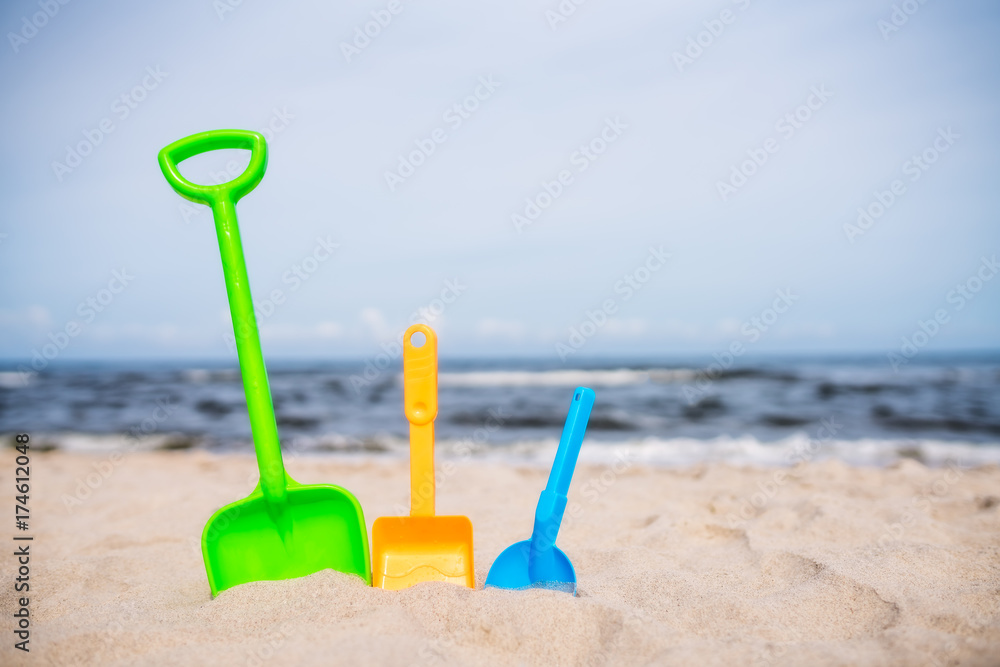 Three colorful toy shovels on the beach Three colorful toy shovels on the beach