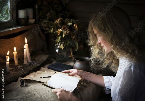 Girl reading a book in the magical mystical ancient dark room with candles