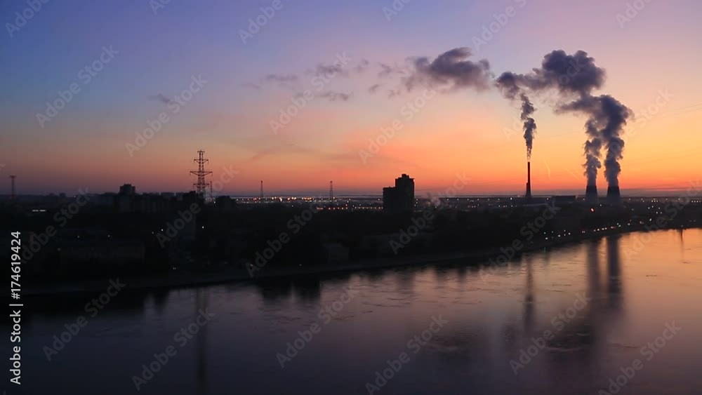 the smoke from the chimneys in the background of the red dawn in the big city with reflection in river the smoke from the chimneys in the background of the red dawn in the big city with reflection in river