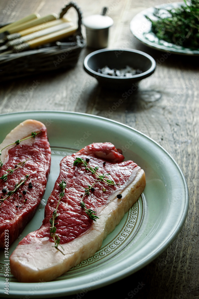Sirloin steaks on a plate with seasoning. Sirloin steaks on a plate with seasoning.
