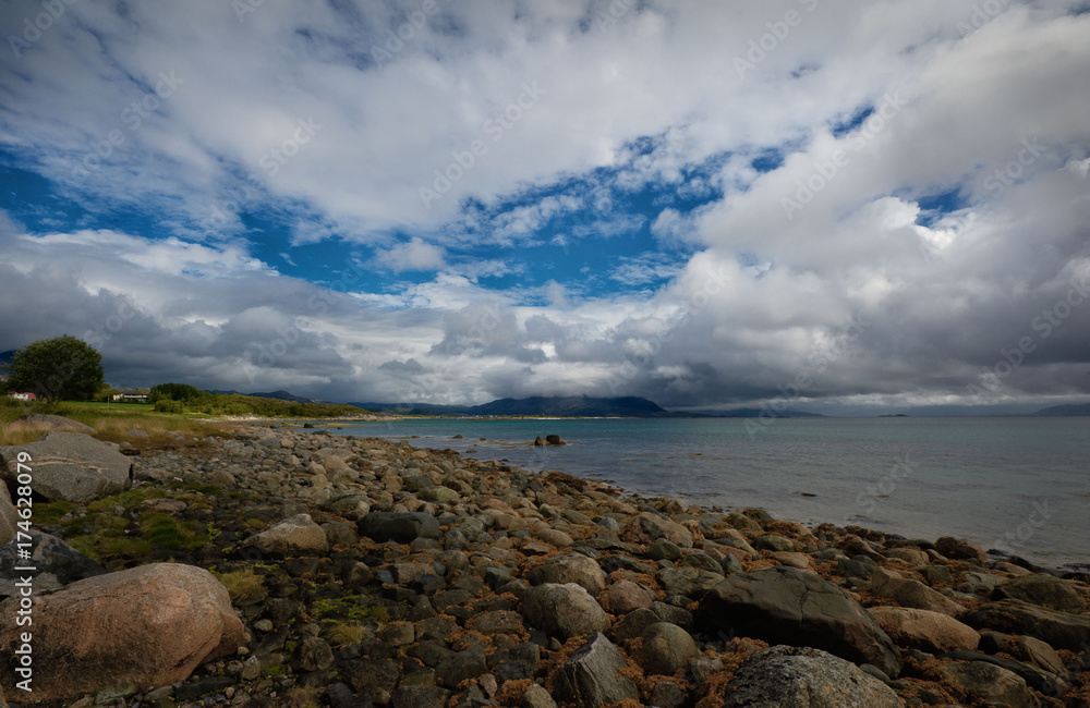 Seascape with stones on the shore and white clouds