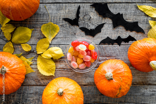 Halloween background. Pumpkins  paper bats and autumn leaves on wooden background top view