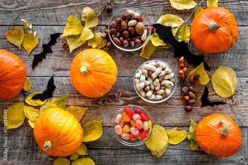Halloween background. Pumpkins, paper bats and autumn leaves on wooden background top view photo