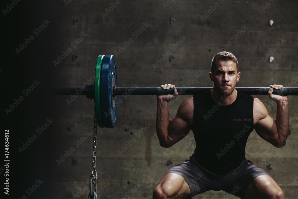 Strong caucasian man lifting weights with chains in gritty workout gym Strong caucasian man lifting weights with chains in gritty workout gym