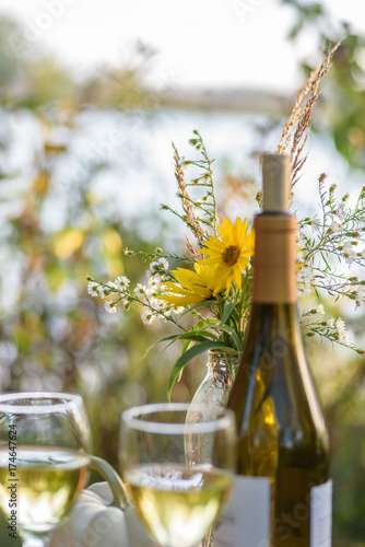 wine glasses and bottle outside with wildflowers