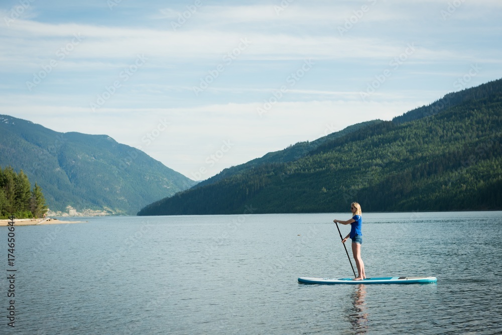 Side view of woman paddleboarding in lake Side view of woman paddleboarding in lake