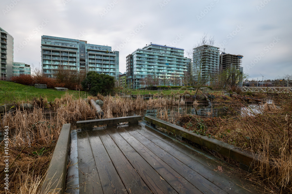 New apartment buildings around a beautiful park in False Creek, Vancouver, British Columbia, Canada. Taken during a cloudy sunrise in spring time.
