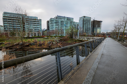 New apartment buildings around a beautiful park in False Creek, Vancouver, British Columbia, Canada. Taken during a cloudy sunrise in spring time.