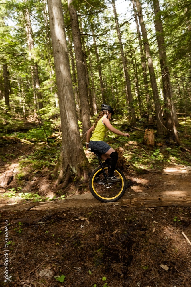 Side view of woman unicycling on trail Side view of woman unicycling on trail