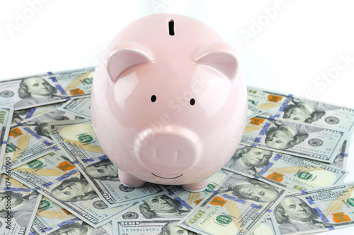 Pink piggy bank on US dollars isolated on white background