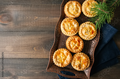 Mini meat pies from flaky dough on a wooden board over wooden background.