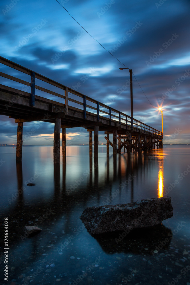 Fototapeta premium Beautiful sunset at the beach by the wooden quay. Taken in Blackie Spit, Whiterock, Greater Vancouver, British Columbia, Canada.