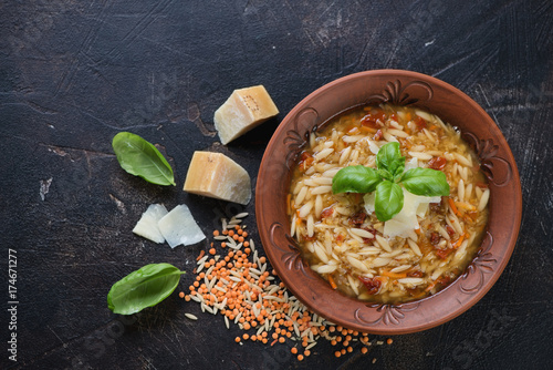Italian soup with lentils and pasta on a dark brown scratched metal background, above view