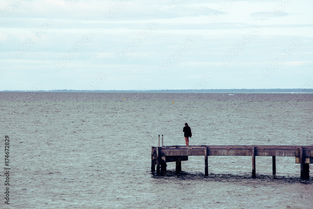 海の桟橋に立っている女性