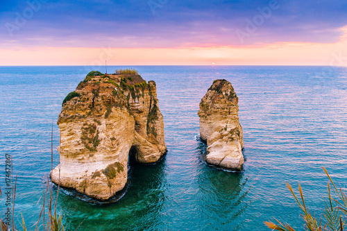 Beautiful sunset on Raouche, Pigeons' Rock. In Beirut, Lebanon.Sun and Stones are reflected in water.dense clouds in the sky. photo