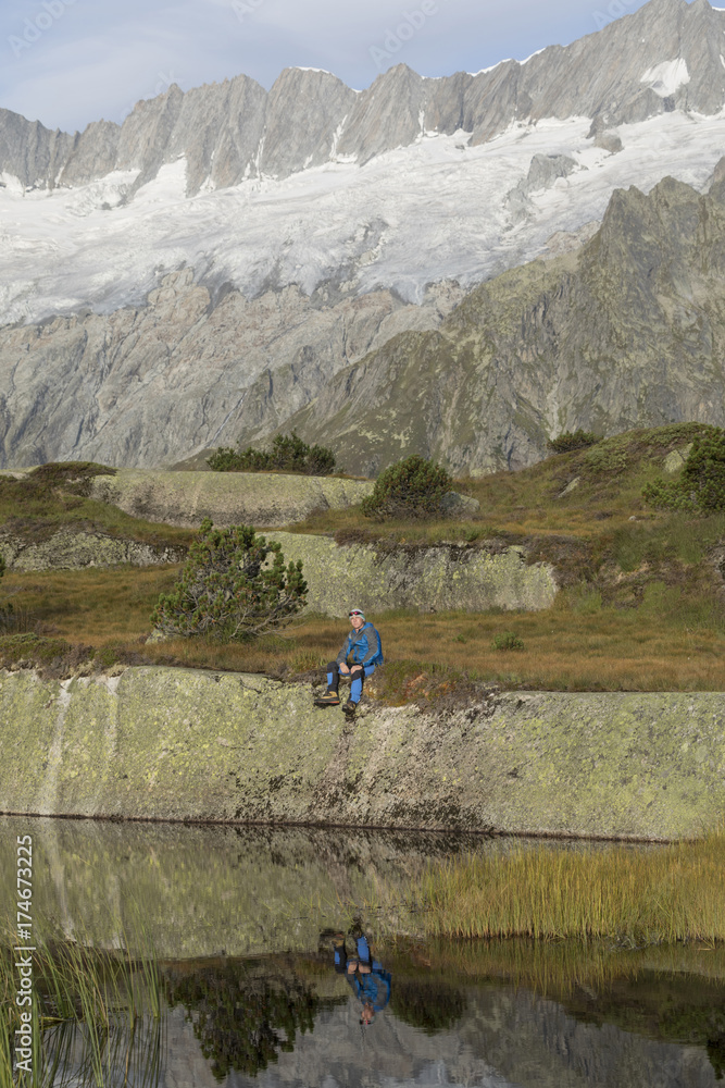 Hiker makes a break at a mountain lake in the Alps in Switzerland