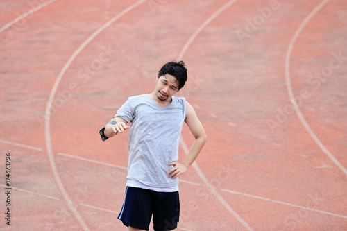 Portrait of young healthy Asian man standing on track in the stadium © tuaindeed