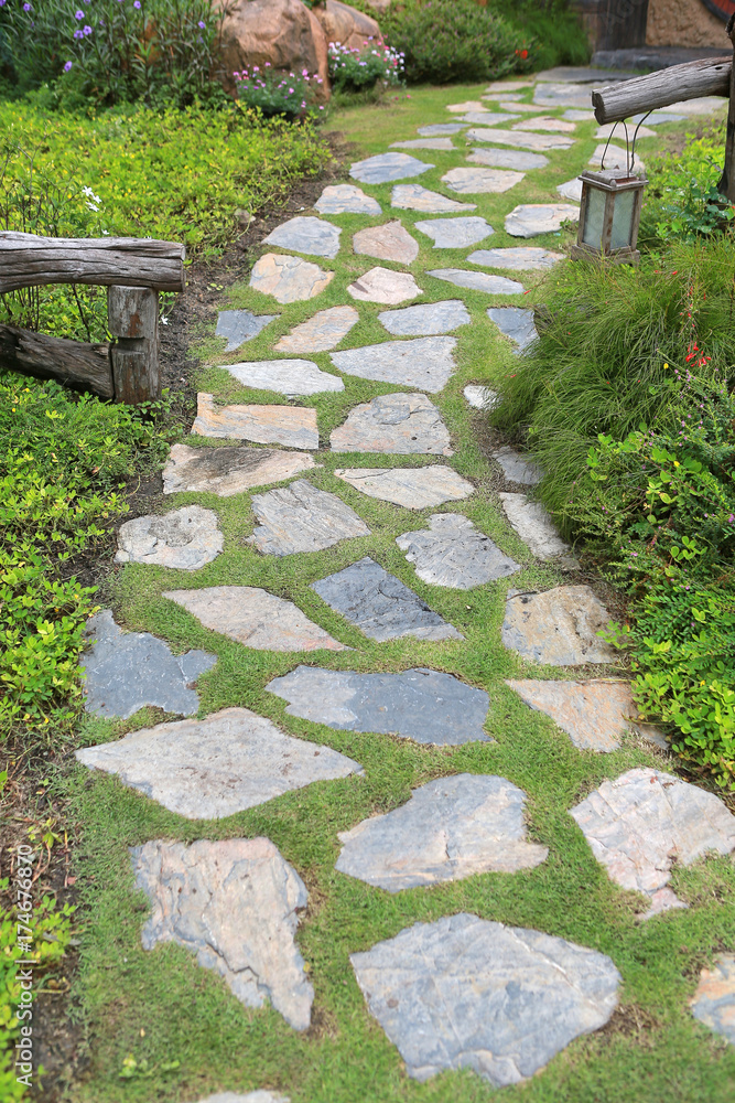 Stone pathway in the park with green grass background.