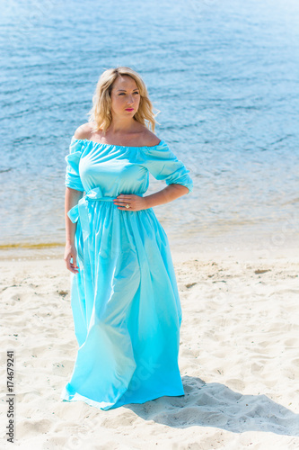 Woman wear in long blue dress on a vacation with romantic mood on a beach near sand and blue water