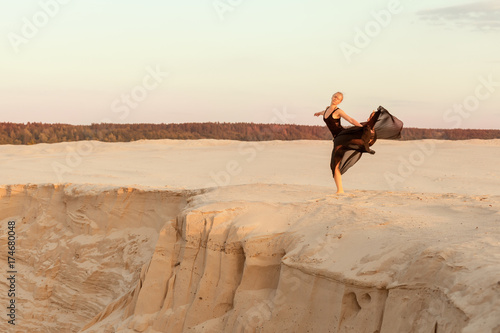 Female dancer performs on a sand dune, she performs the performance.
