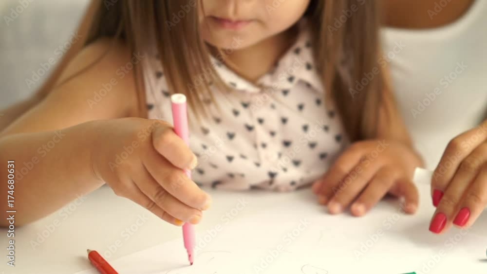 Cropped Close up view of young asian woman sitting by the table with her daughter and draws together Cropped Close up view of young asian woman sitting by the table with her daughter and draws together