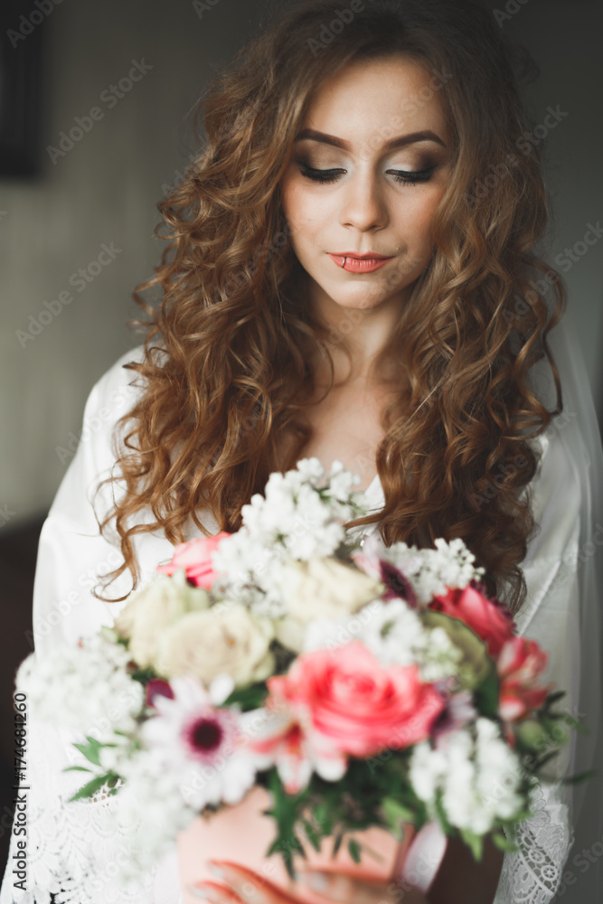 Gorgeous bride in robe posing and preparing for the wedding ceremony face in a room