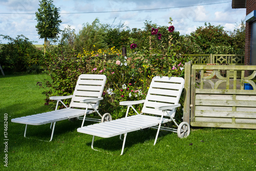 Zwei weiße Liegestühle im Garten