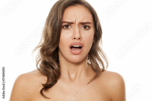 Portrait of beautiful young negatively surprised woman on white background