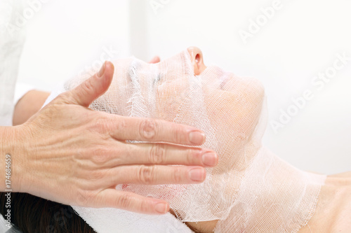 Kosmetyczka nakłada maskę na twarz kobiety. Kobieta w salonie kosmetycznym podczas zabiegu pielęgnacyjnego 