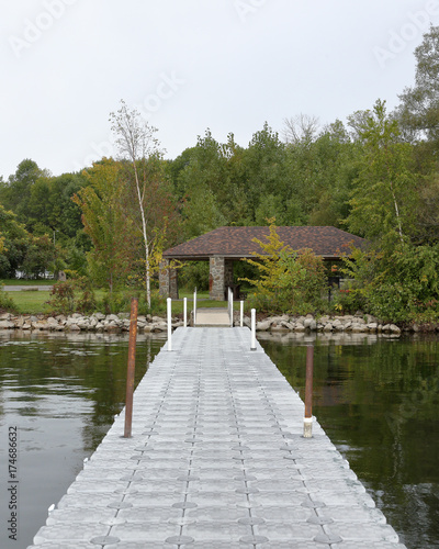 Small dock looking toward the riverbank at at park with trees