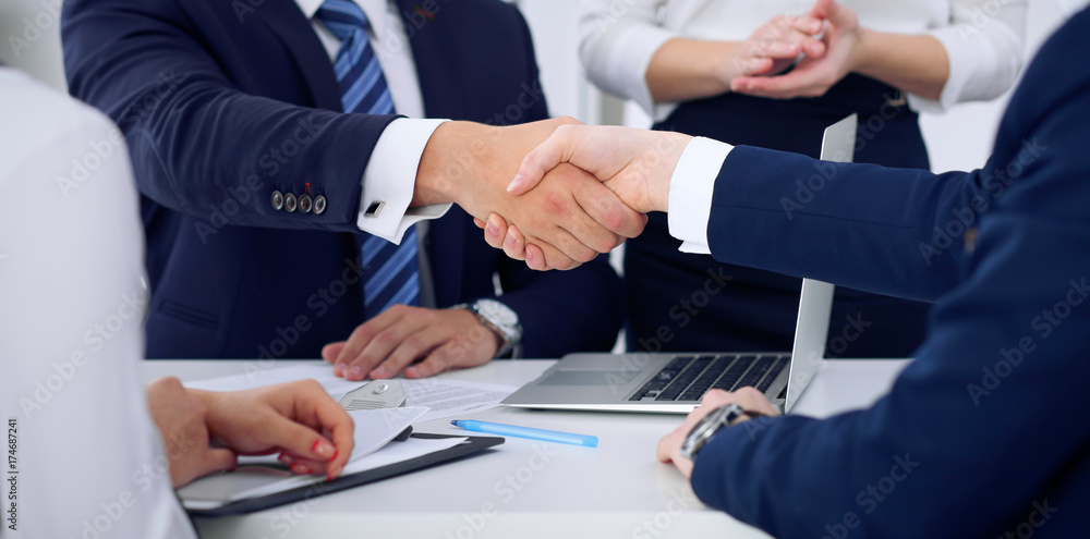 Business handshake at meeting or negotiation in the office, close-up. Partners are satisfied because signing contract or financial papers Business handshake at meeting or negotiation in the office, close-up. Partners are satisfied because signing contract or financial papers