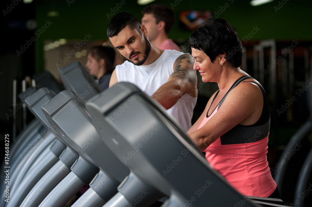 Fitness coach assisting his client on treadmill Fitness coach assisting his client on treadmill
