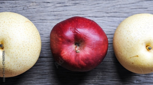 raw organic of 2 yellow Asian apple pears and 1 red apple in the middle on wooden table background photo