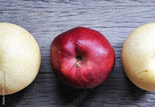 raw organic of 2 yellow Asian apple pears and 1 red apple in the middle on wooden table background photo