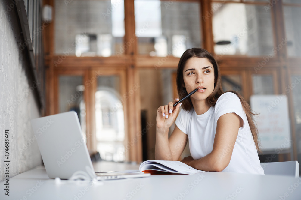 Obraz premium Beautiful girl studying in public library preparing for her graduation. Chosing career is not as easy as it seems. Education concept.