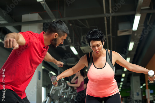 Middle aged female client working out with weights