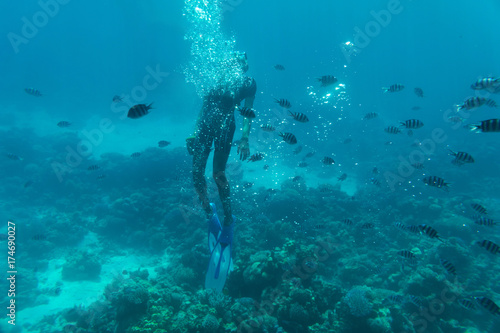 The man floats under water on coral reefs