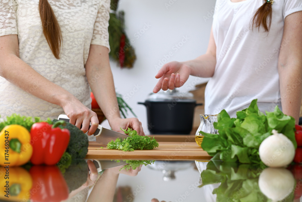 Close-up of human hands cooking in a kitchen. Friends having fun while preparing fresh salad. Vegetarian, healthy meal and friendship concept Close-up of human hands cooking in a kitchen. Friends having fun while preparing fresh salad. Vegetarian, healthy meal and friendship concept