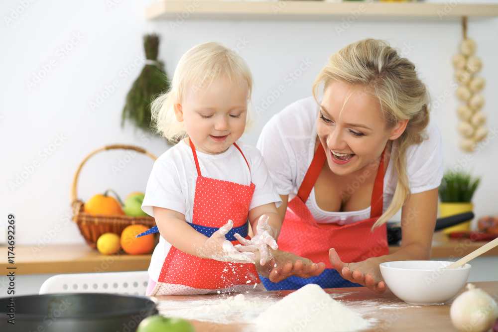 Mother and little daughter are cooking in the kitchen. Spending time all together or happy family concept Mother and little daughter are cooking in the kitchen. Spending time all together or happy family concept