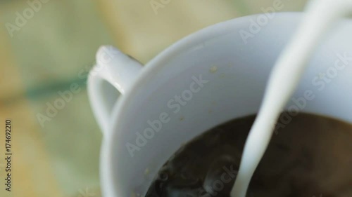 Macro detail of pouring milk in black coffee