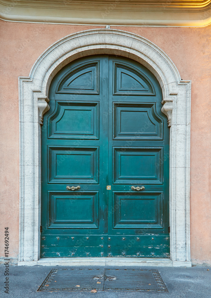 Ancient green door with golden handles in Rome, Italy