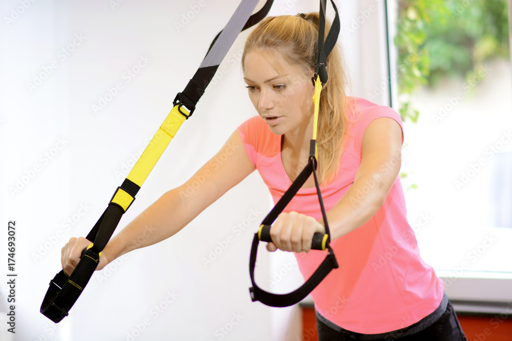 Frau im Fitnessstudio trainiert mit TRX Bändern Frau im Fitnessstudio trainiert mit TRX Bändern