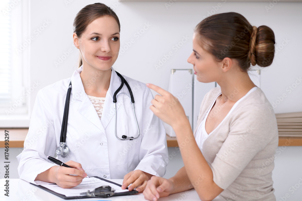 Doctor and patient sitting at the desk. The physician or therapist makes a diagnosis. Health care, medicine and patient service concept Doctor and patient sitting at the desk. The physician or therapist makes a diagnosis. Health care, medicine and patient service concept