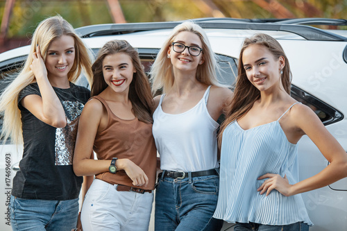 The young women standing near the car